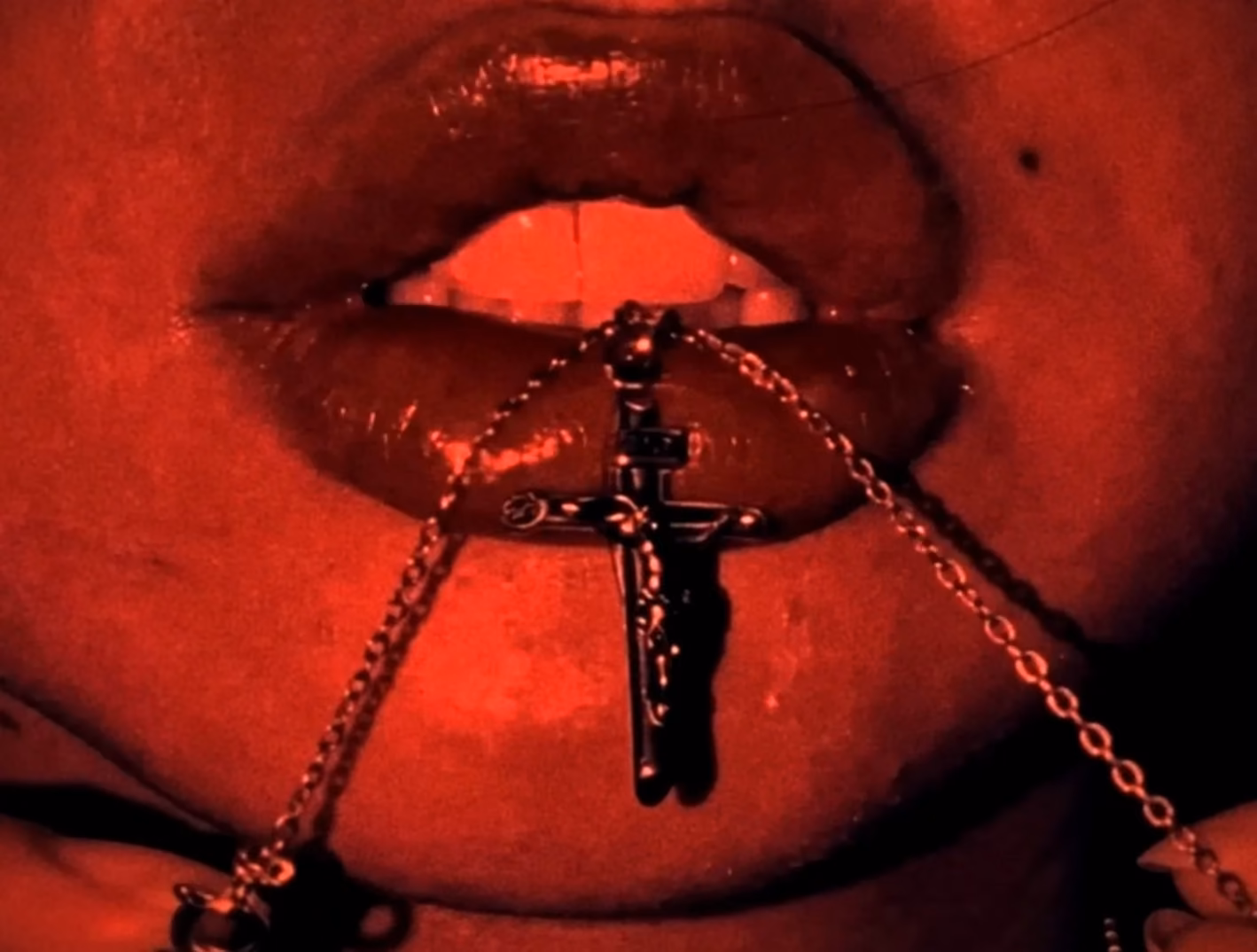 Close-up of lips and a cross chain under red light