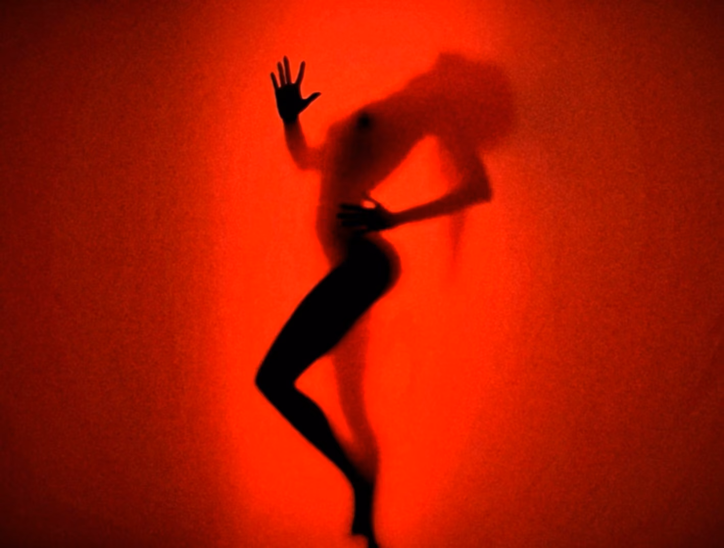 A dancing figure appearing as a shadow through saturated red light