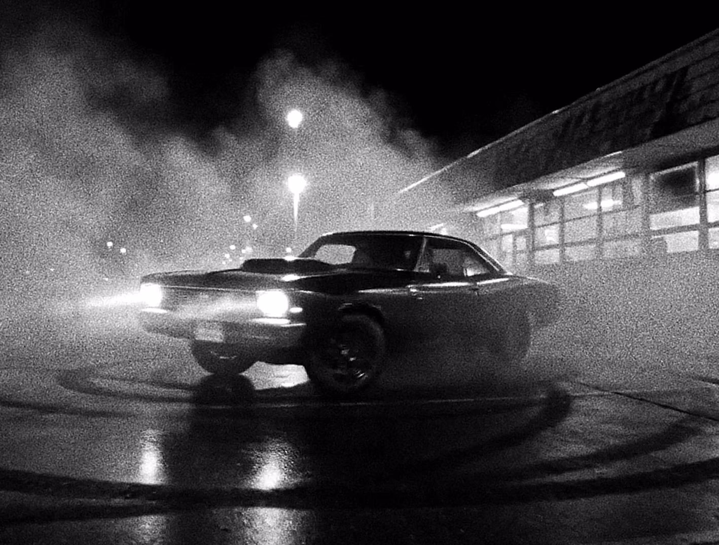 Classic car drifting through a smoky street at night