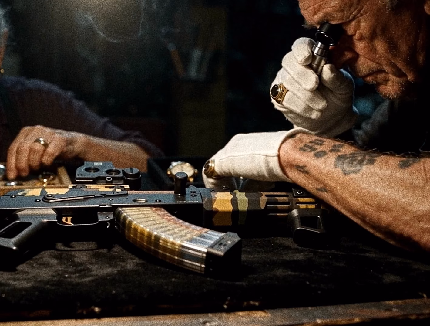 Tattooed craftsperson working on a precision object at a bench