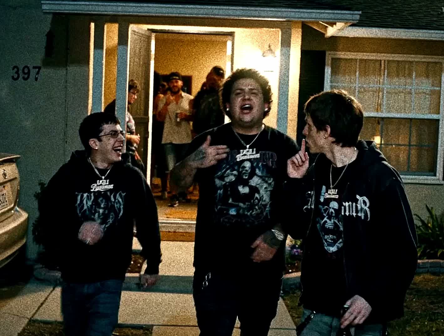 Three characters in UGLi Business streetwear outside a warmly lit house at night
